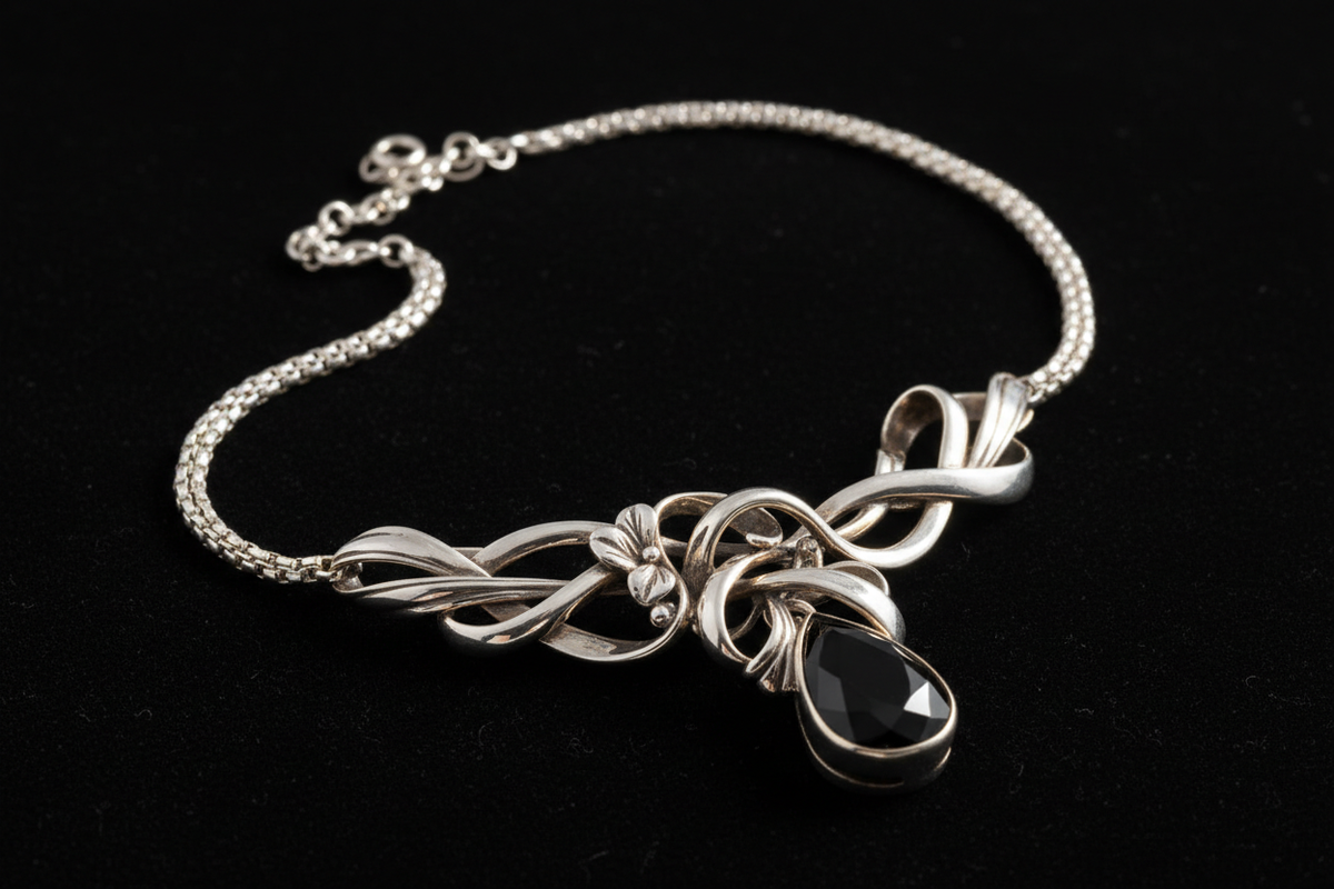 “Create a luxury editorial-style image of a handcrafted 925 sterling silver necklace displayed on a soft matte black background. Use premium studio lighting, sharp reflections, smooth shadows, and a high-gloss metallic finish. Add a subtle gold-tinted rim light to enhance the silver texture. Style the shot like a high-fashion jewellery magazine.”