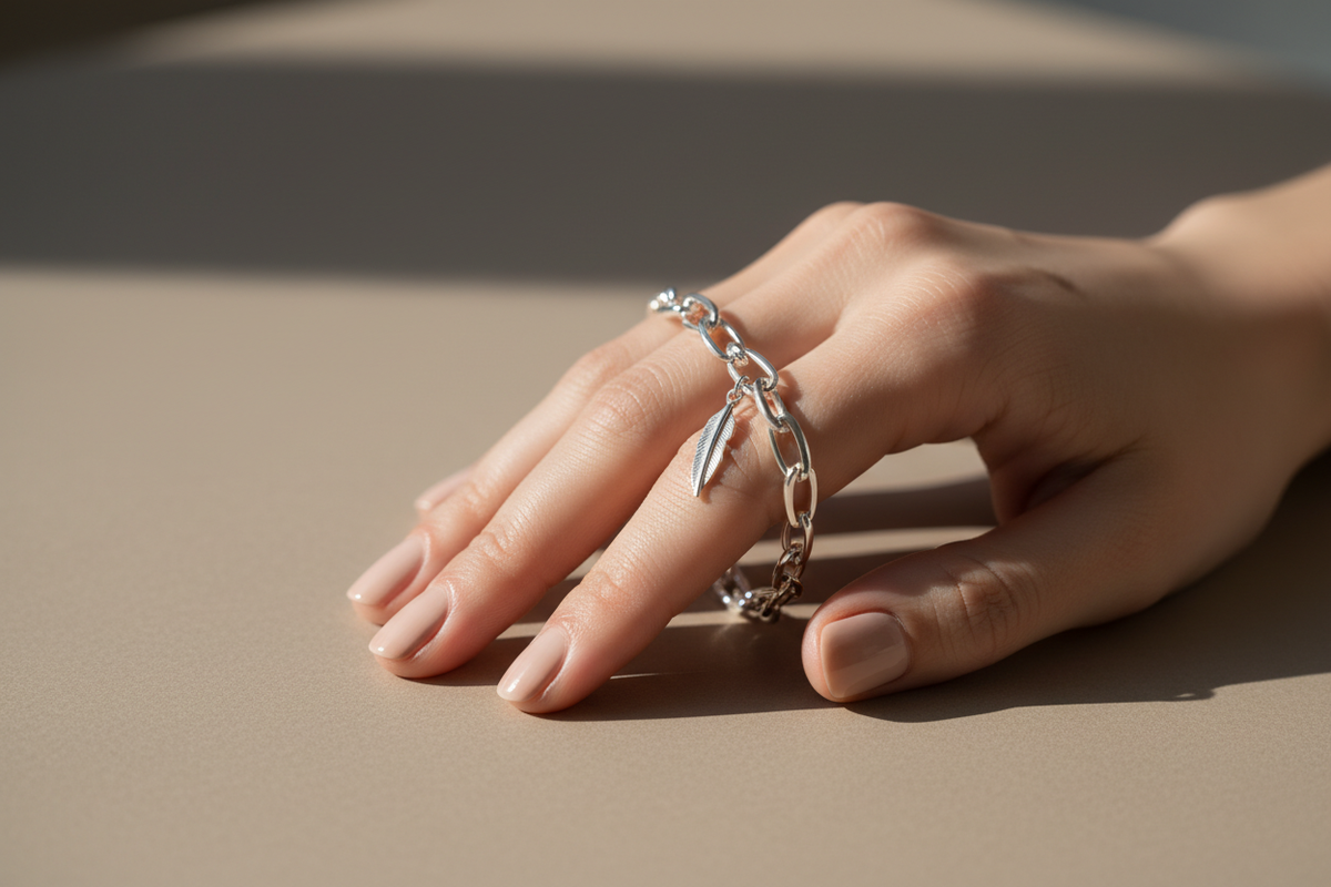 “Generate a close-up lifestyle image of a person’s hand wearing an elegant 925 silver bracelet. Use natural lighting, a minimal background (beige or muted grey), and a soft shadow effect. Capture fine details, reflections, and craftsmanship. Style it like a premium lifestyle jewellery campaign.”
